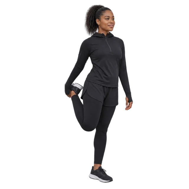A woman in black athletic clothing standing on one leg while holding her other foot behind her