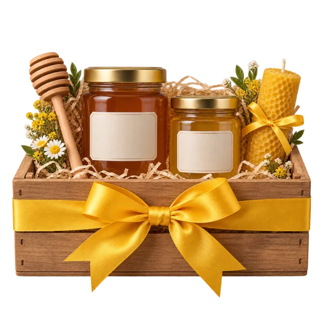 A wooden crate holding honey jars, a wooden dipper and a rolled honeycomb-textured candle, tied with a yellow bow