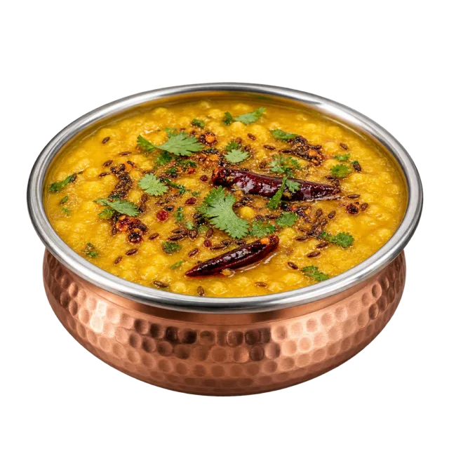 Yellow lentil curry in a hammered copper-colored bowl topped with dried red chilies and green herbs