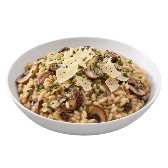 A shallow bowl of creamy rice with sliced mushrooms, shaved cheese and chopped green herbs