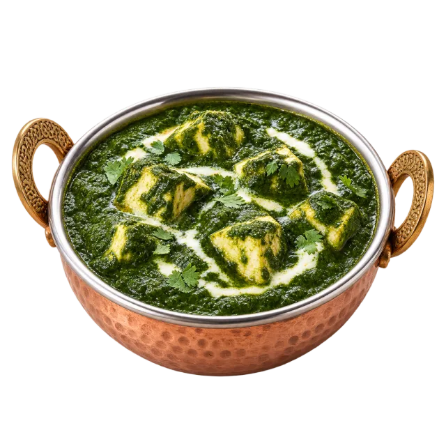 A handled copper-colored bowl of green spinach curry with paneer cubes and a pale cream swirl