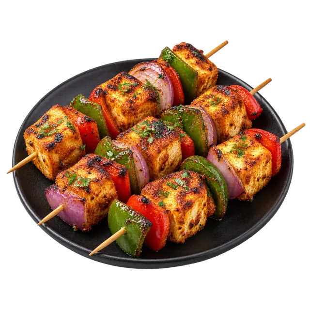 Grilled paneer cubes threaded on skewers with green peppers and red onion on a dark plate