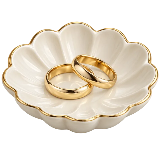 Two gold-colored rings sit in a shell-shaped pale dish