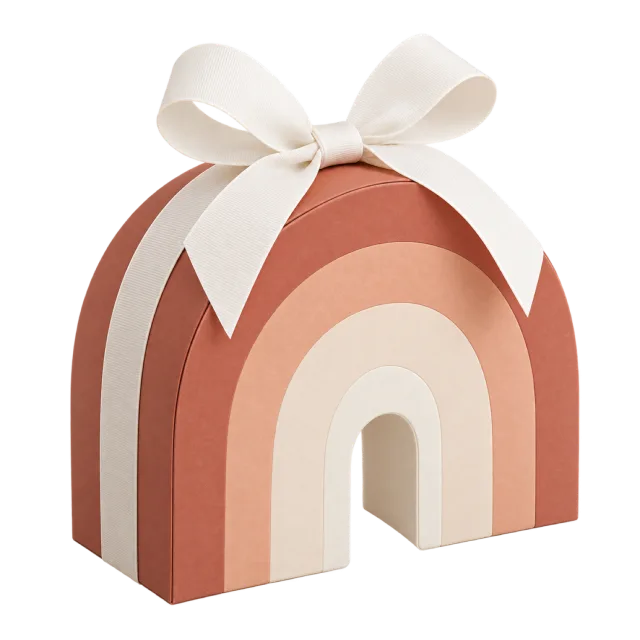 A rainbow-arch box in muted peach, pink and cream tones with a white bow