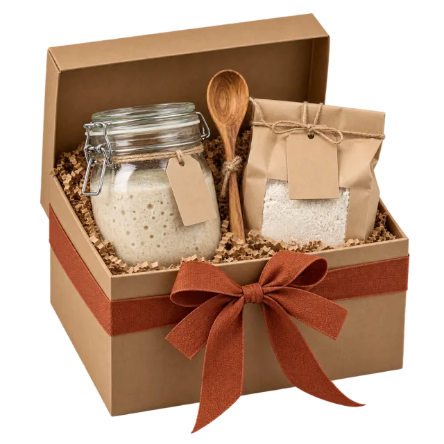 An open kraft gift box with a glass jar, wooden spoon and paper bag, tied with a rust-colored bow