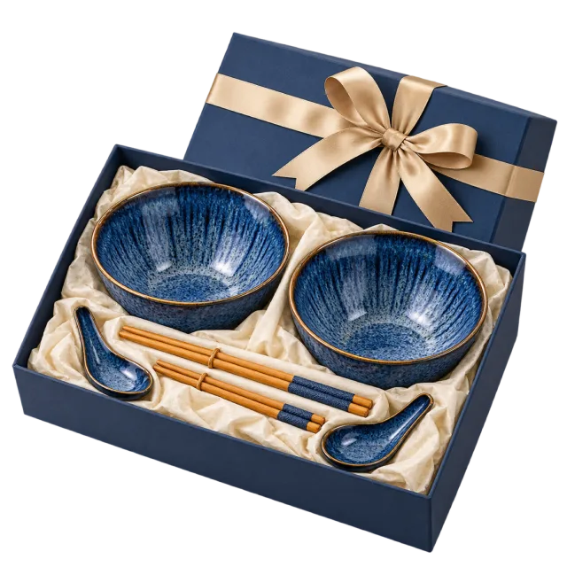 A navy gift box holding two blue bowls, chopsticks and matching spoons in a pale lining