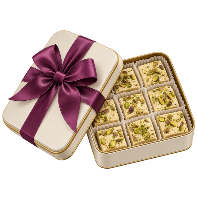 A cream tin holding square nut-topped sweets with a plum-colored bow on its lid