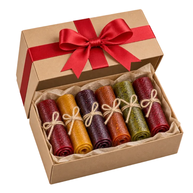A kraft box containing colorful rolled fruit strips tied with small bows, under a red ribboned lid