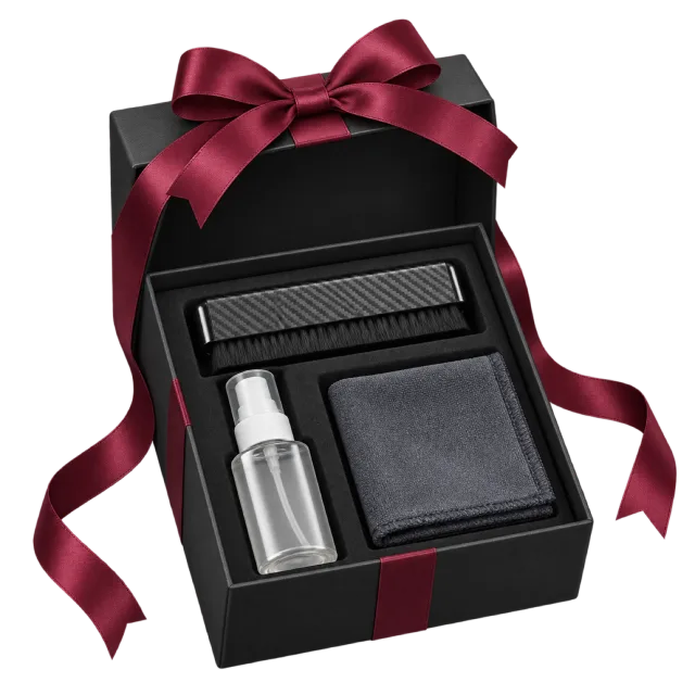 A black gift box with a record-cleaning brush, small spray bottle and dark cloth, tied with burgundy ribbon