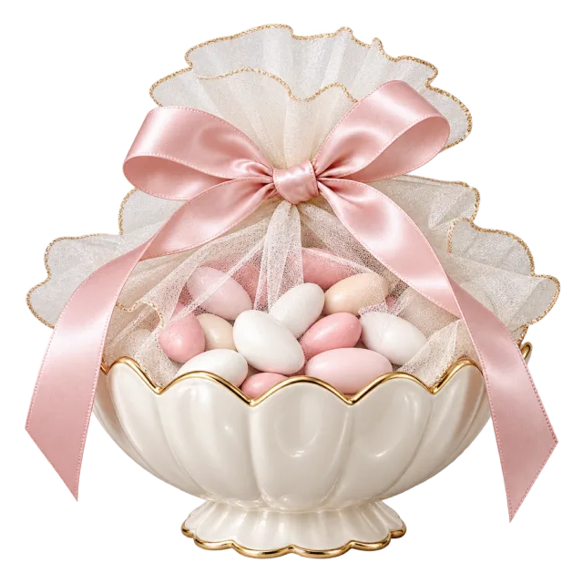 Cream scalloped bowl filled with pastel almond-shaped sweets beneath pink ribbon and sheer wrapping