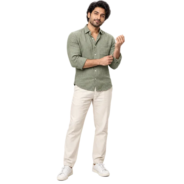 Man adjusting his sleeve while wearing a sage green shirt and cream trousers