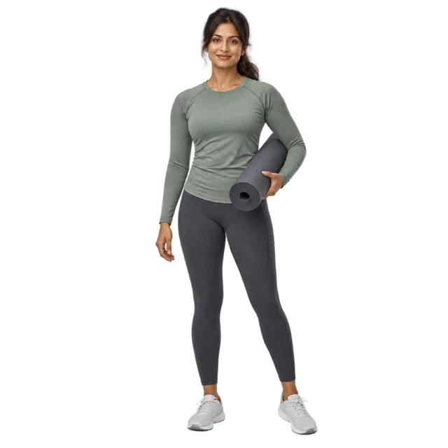Woman in a sage long-sleeved top and dark leggings holding a rolled exercise mat