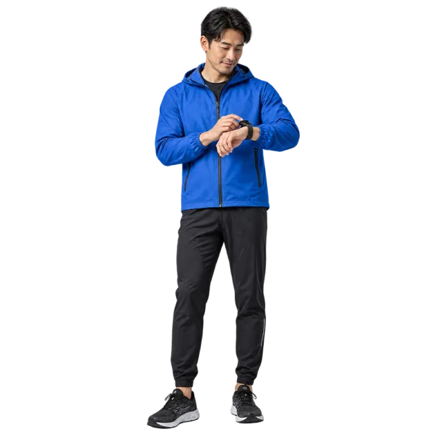 Man in a blue athletic jacket and black trousers looking at his wrist