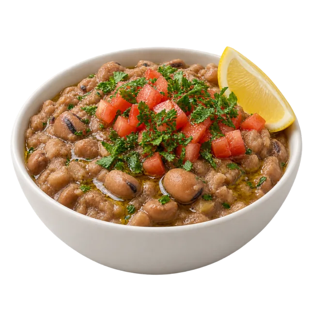 Ful medames in a white bowl with beans, chopped tomato, green herbs and a lemon wedge
