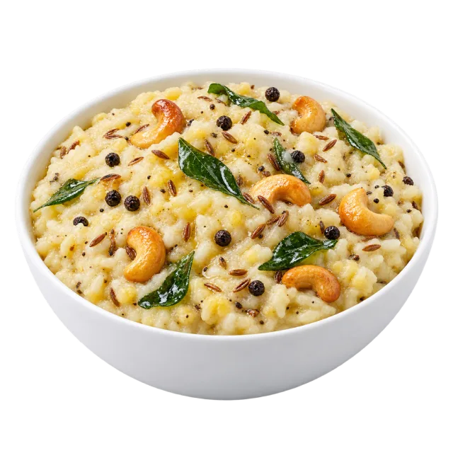 Pale ven pongal topped with cashews, peppercorns and green leaves