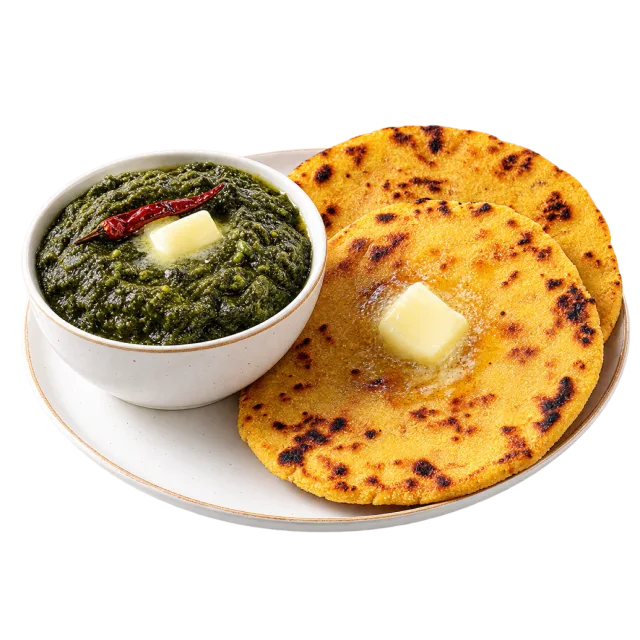Saag in a small bowl beside golden makki roti topped with butter