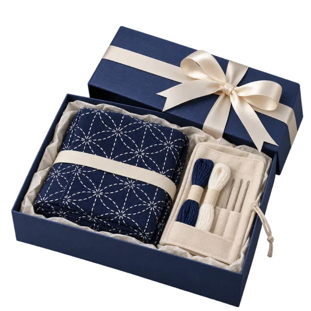 Navy stitching gift kit with patterned blue fabric, thread and an ivory bow