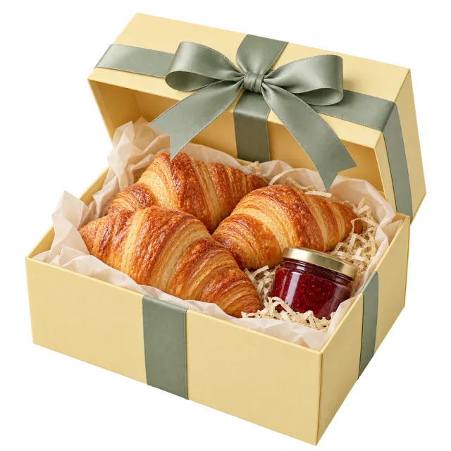 Pale yellow gift box with croissants, a jam jar and a sage bow