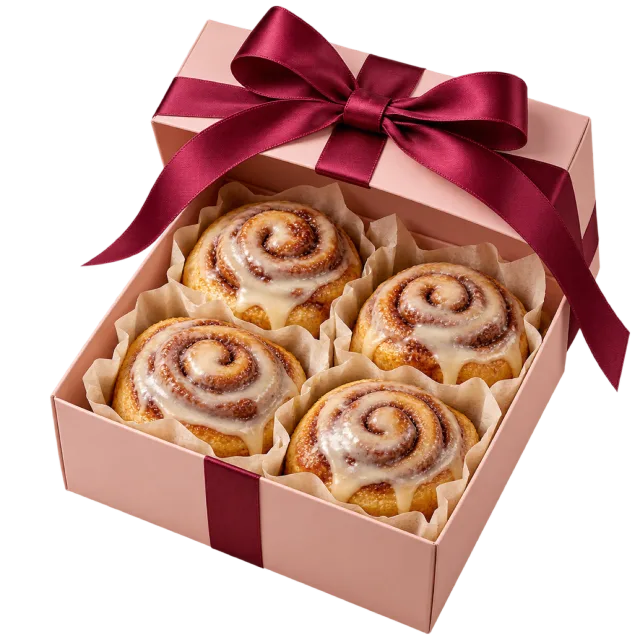 Pink gift box filled with iced cinnamon rolls and topped with a burgundy bow