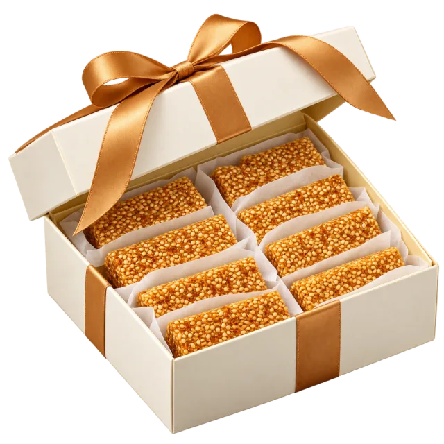 Cream compartmented gift box containing sesame brittle bars and a golden bow