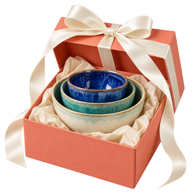 Coral gift box with stacked blue and green ceramic bowls and an ivory bow