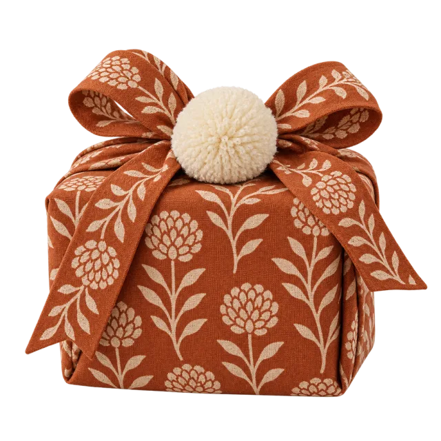 Rust-colored floral cloth parcel topped with a cream pompom