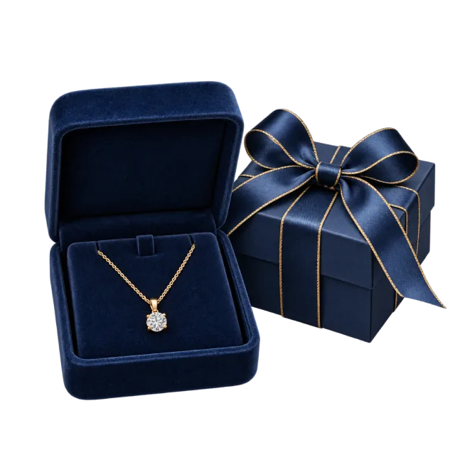 An open navy velvet jewelry box holding a pendant necklace beside a ribbon-tied package